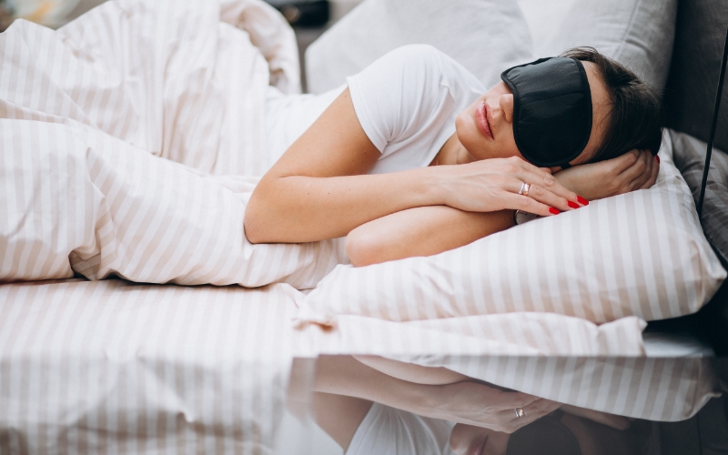 Woman with black sleeping mask on asleep in bed