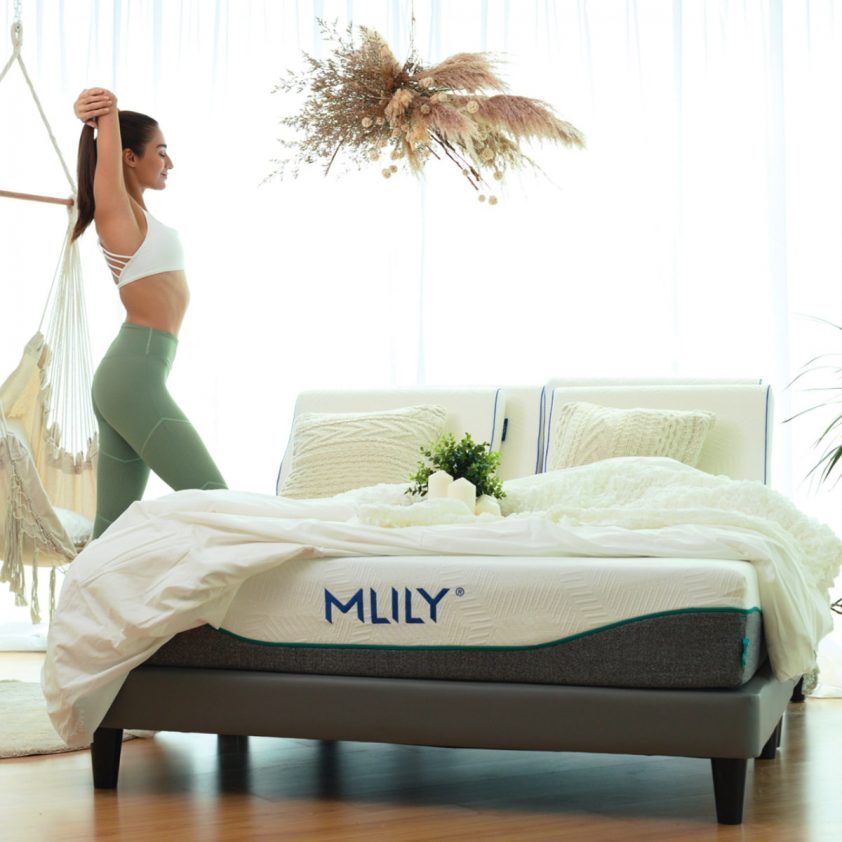 Woman stretching in green yoga attire next to MLily mattress